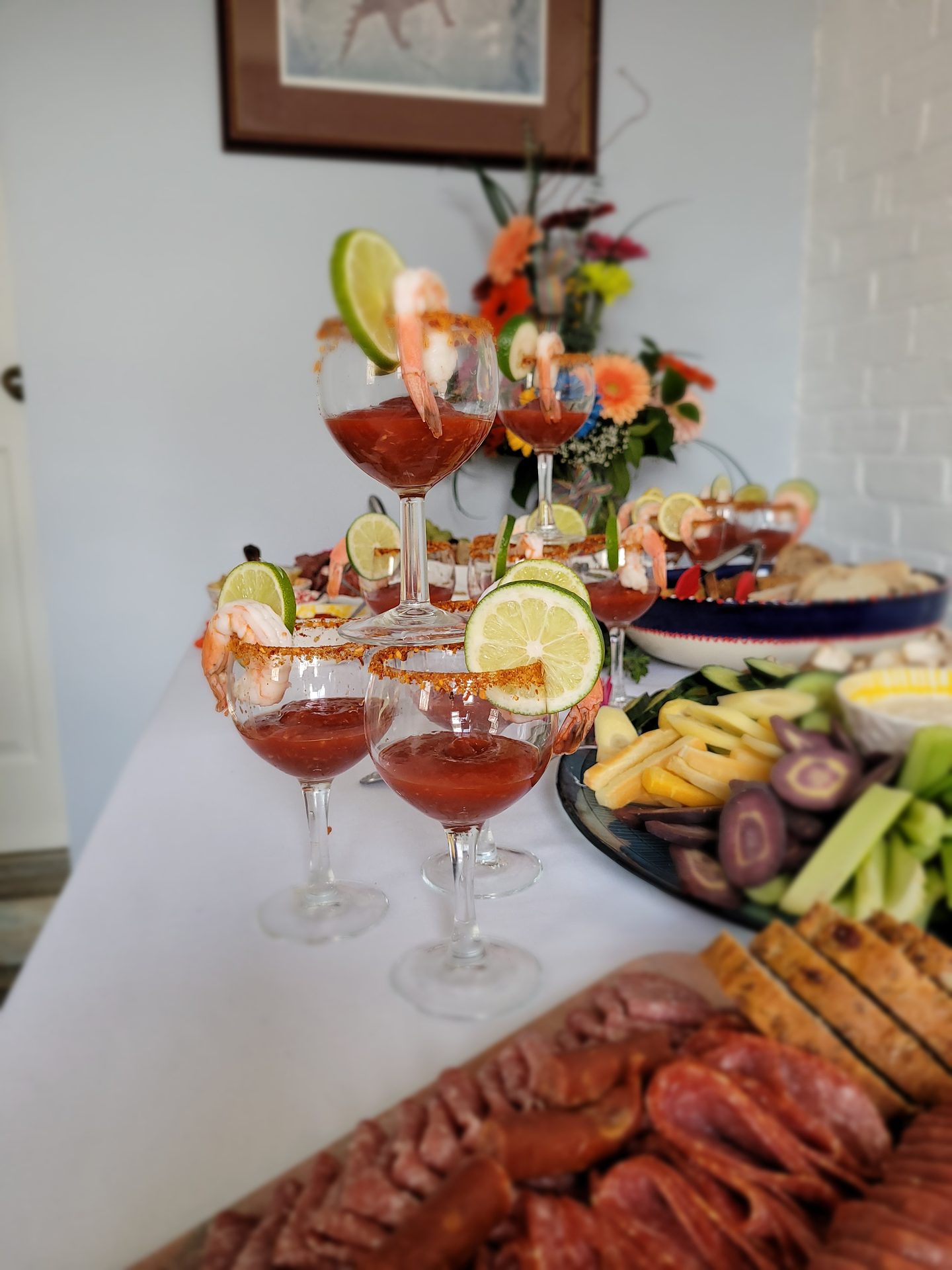 Shrimp cocktail martini glasses beside a charcuterie board